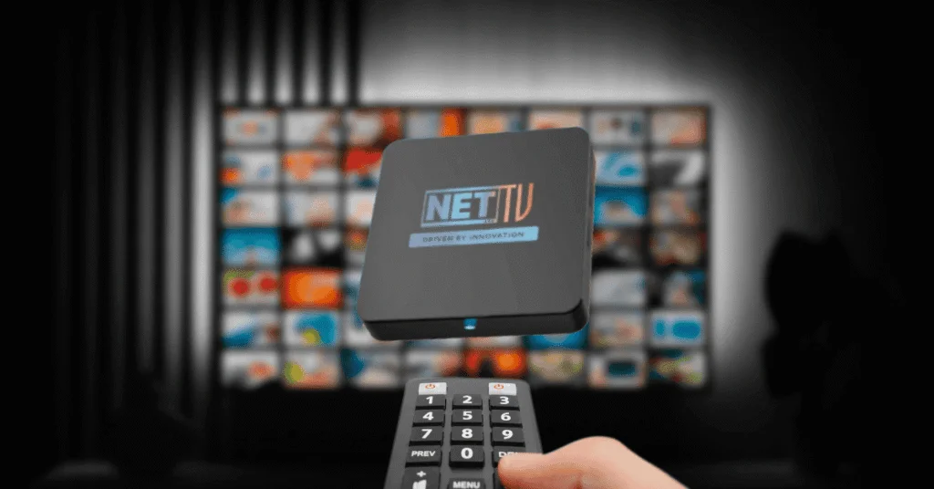A person holding a remote and Worldlink NETTV device in front of a TV displaying multiple channels